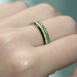 Green garnet ring in 18ct white gold on a hand stacked next to other eternity rings.