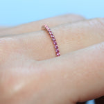 Closeup of a pink sapphire eternity ring in 18ct rose gold on a hand