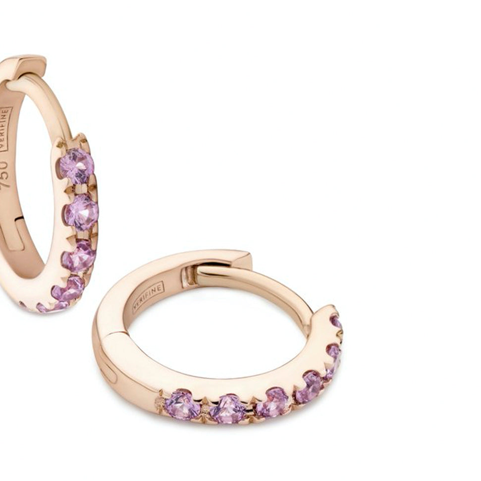 Close up of pink sapphire huggie earrings in 18ct rose gold on white background